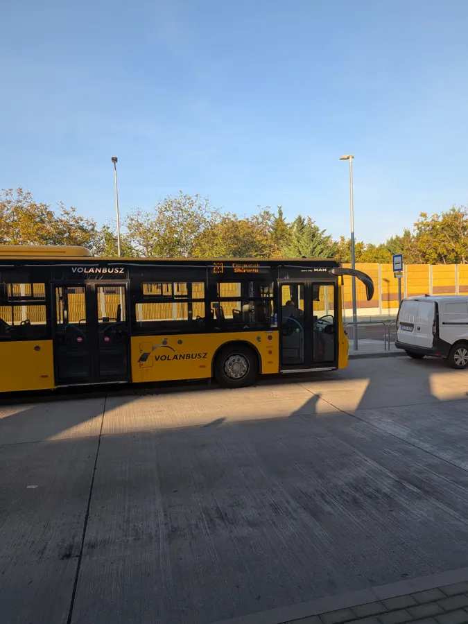 A yellow Volánbusz city bus waiting at a stop