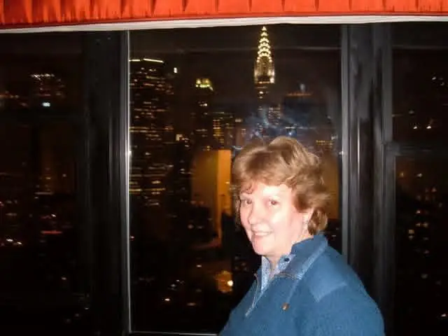 My mom at a hotel window at night with the New York skyline behind her